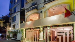A hotel facade with a welcoming entrance, a flag, and decorative plants. -  Singita Classy Boutique Hotel (Hanoi)