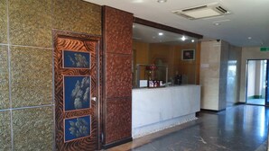 Un espace d’accueil doté d’un sol en marbre, d’un comptoir de réception et d’un mur recouvert de carreaux décoratifs.