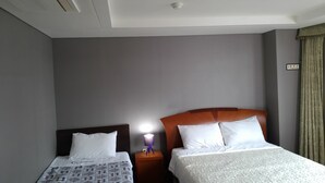 Une chambre d’hôtel avec deux lits, une table de chevet avec une lampe et un luminaire au plafond.