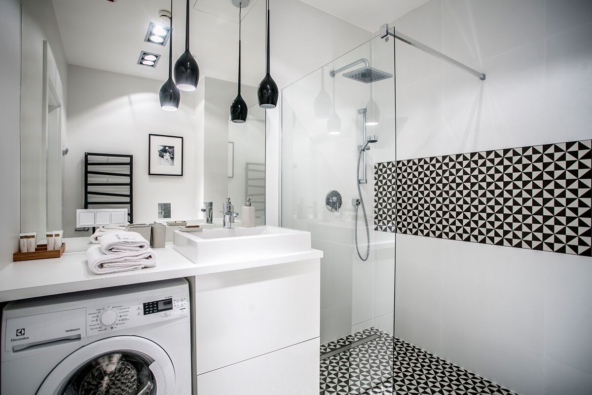 A modern bathroom with a washing machine, a sink, and a shower.