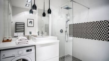 A modern bathroom with a washing machine, a sink, and a shower.