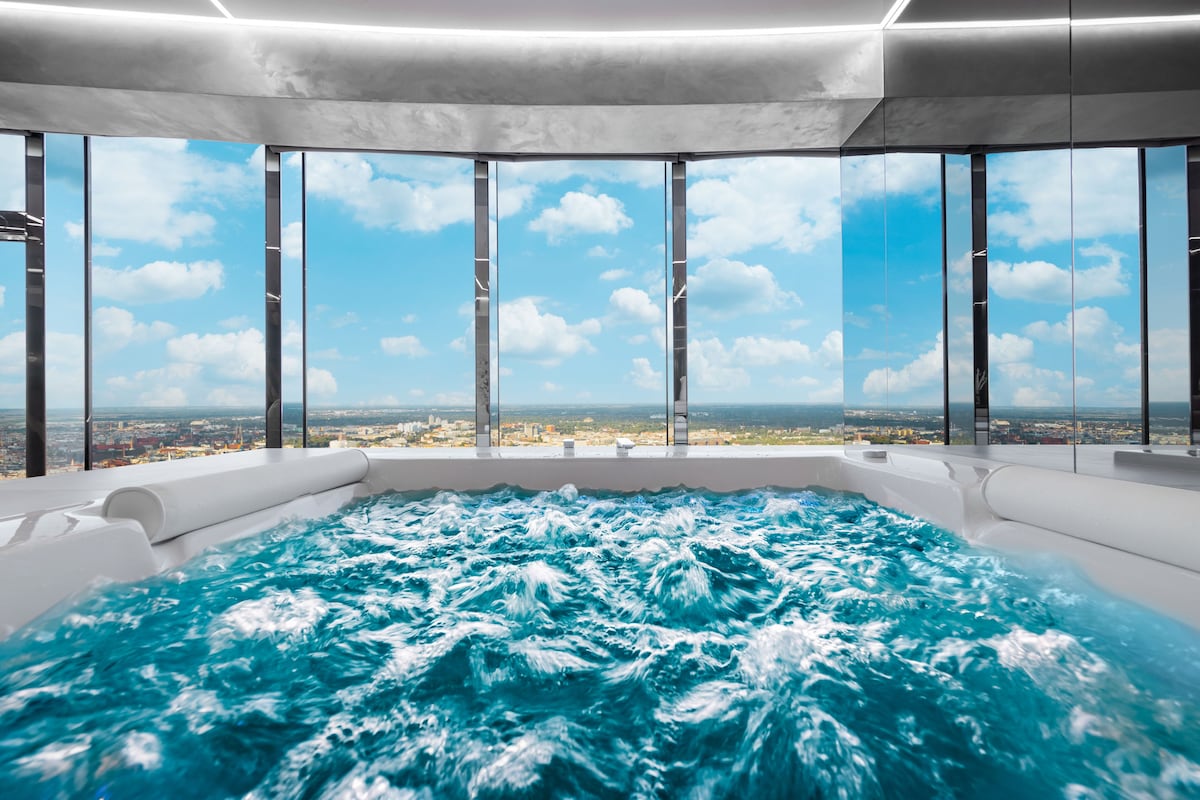 A modern indoor hot tub with a panoramic city view.
