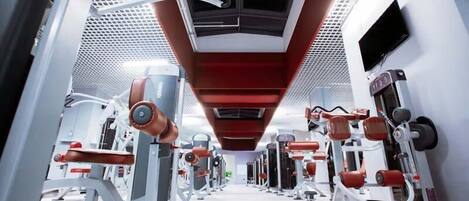 A gym with various exercise machines arranged in rows.
