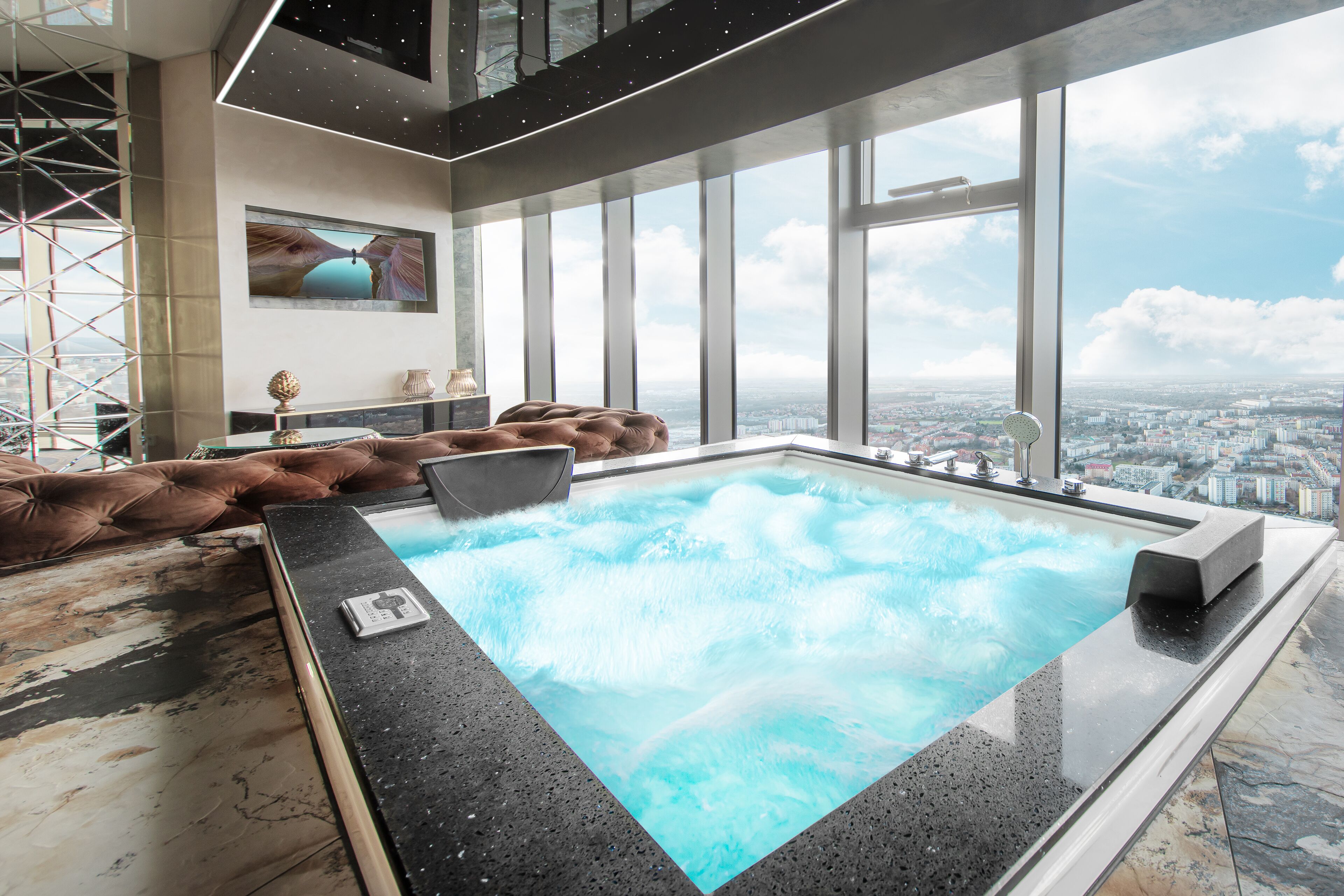 Una piscina interior moderna con vistas a la ciudad, un ventanal grande y un sofá de cuero marrón.