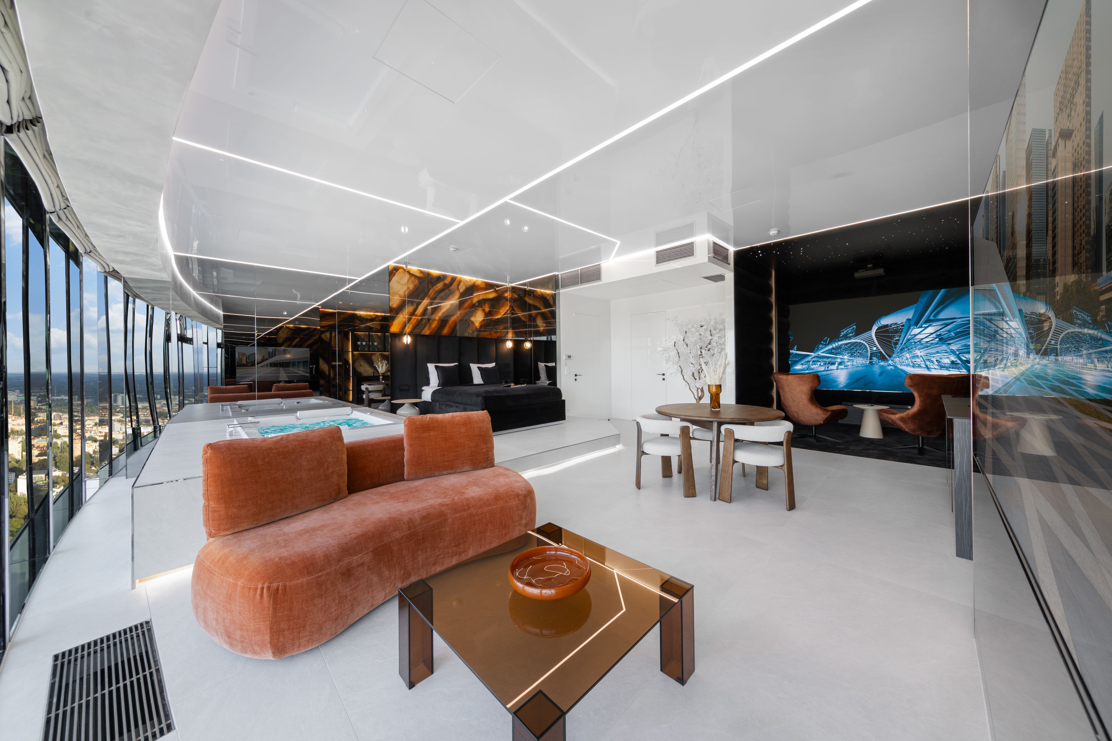 Un interior moderno con sofá, mesa de centro y una gran pantalla digital mostrando un paisaje urbano.