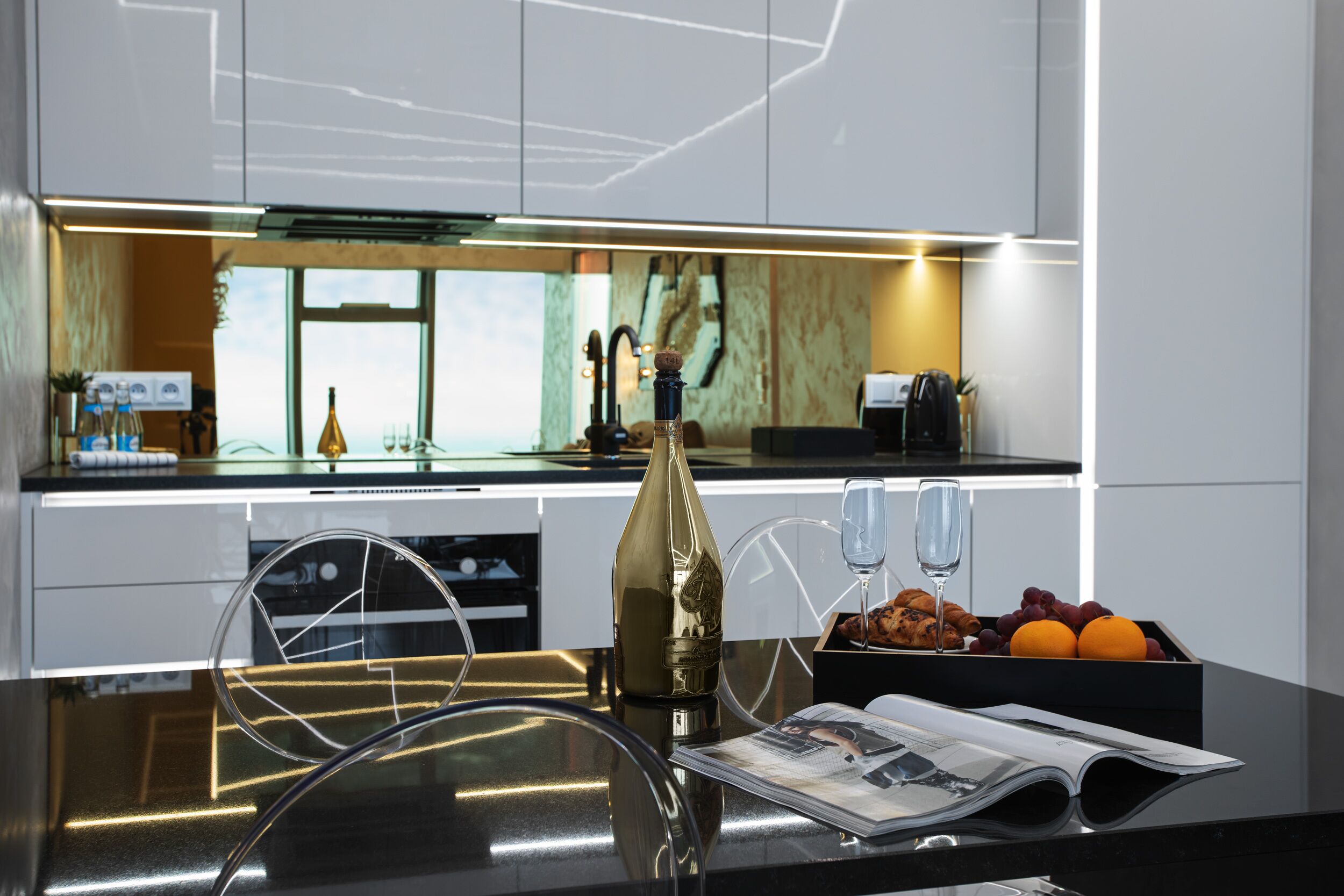 A modern kitchen with a central island, a wine glass, and a fruit bowl.