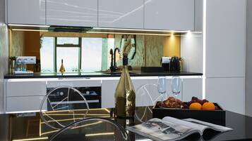 A modern kitchen with a central island, a wine glass, and a fruit bowl.