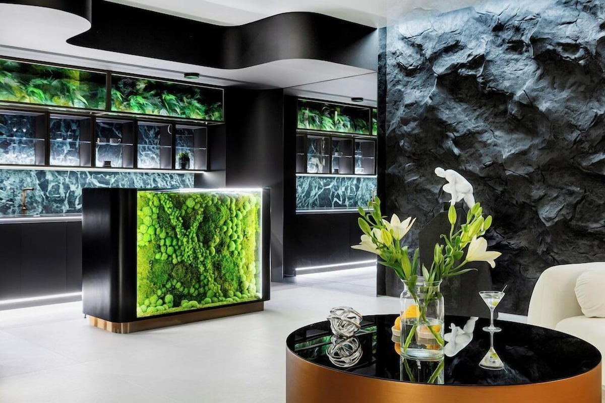 A modern lobby with a reception desk, a black wall with a rocky texture, and a white sofa.