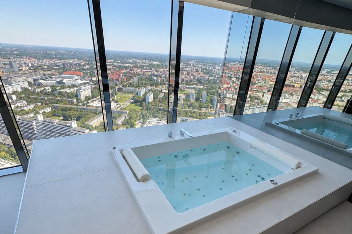 A modern bathroom with a large bathtub and a view of a cityscape through large windows.