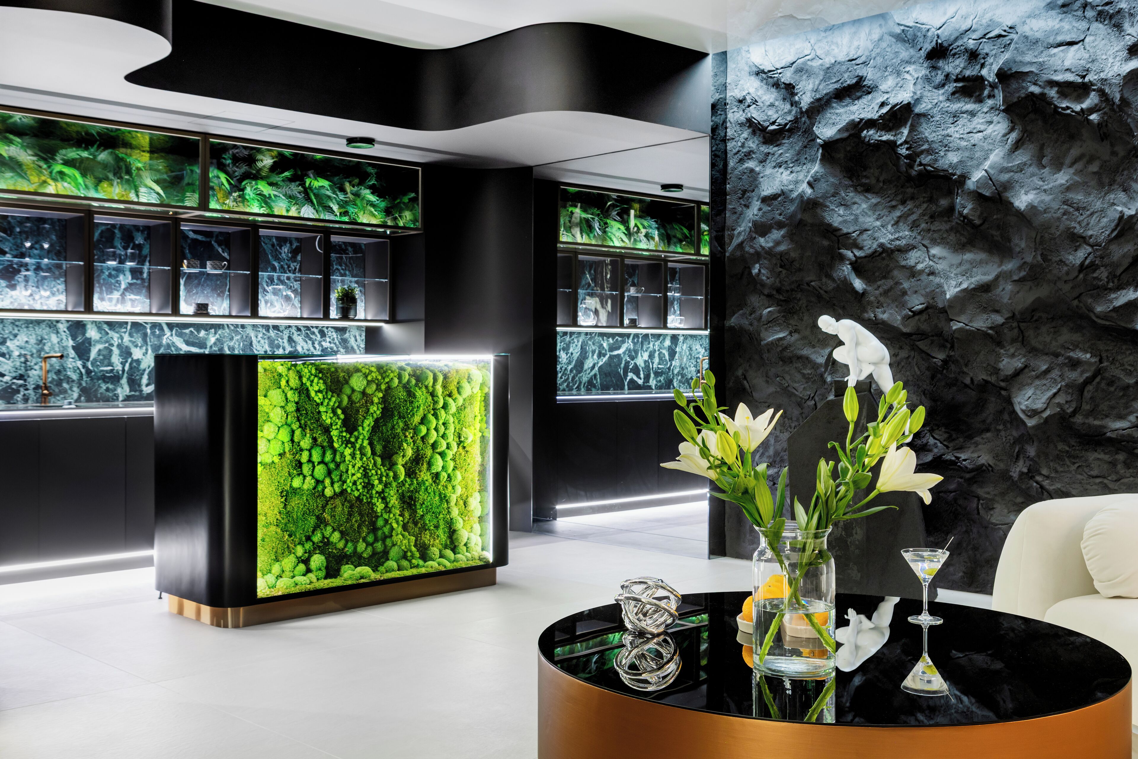 A modern reception area with a black reception desk, green wall with aquarium, and a white sofa.