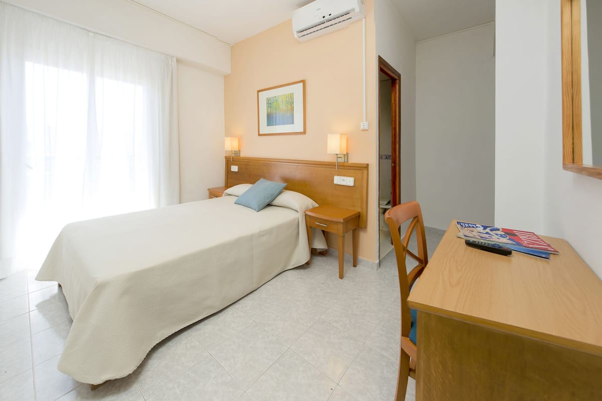 Ein Hotelzimmer mit einem Bett, Nachttischen, einem Schreibtisch und einem Sessel.