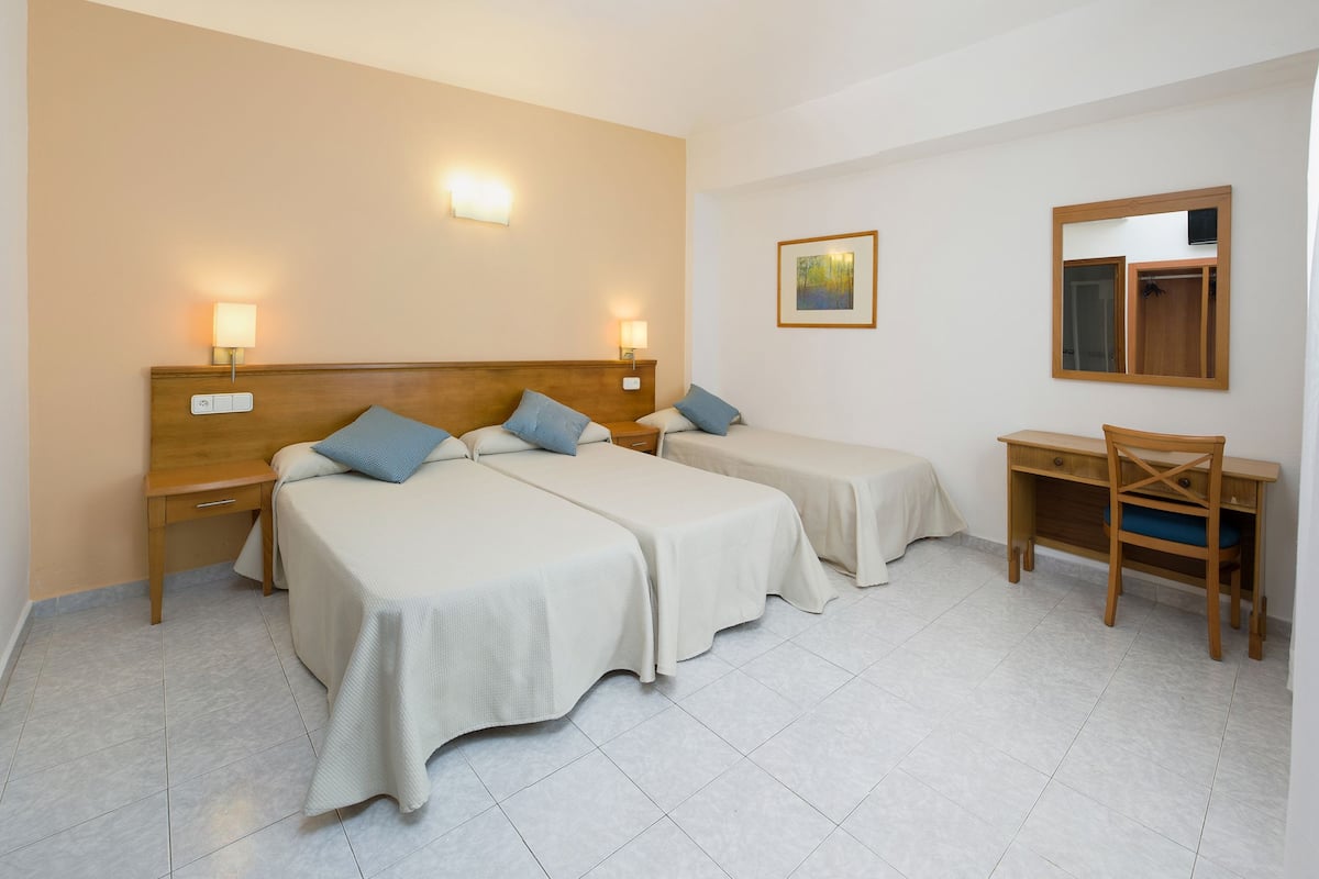 Ein Hotelzimmer mit zwei Betten, einem Schreibtisch und einem Stuhl.