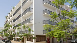 Un immeuble à plusieurs étages doté de balcons, une rue devant et quelques espaces verts.