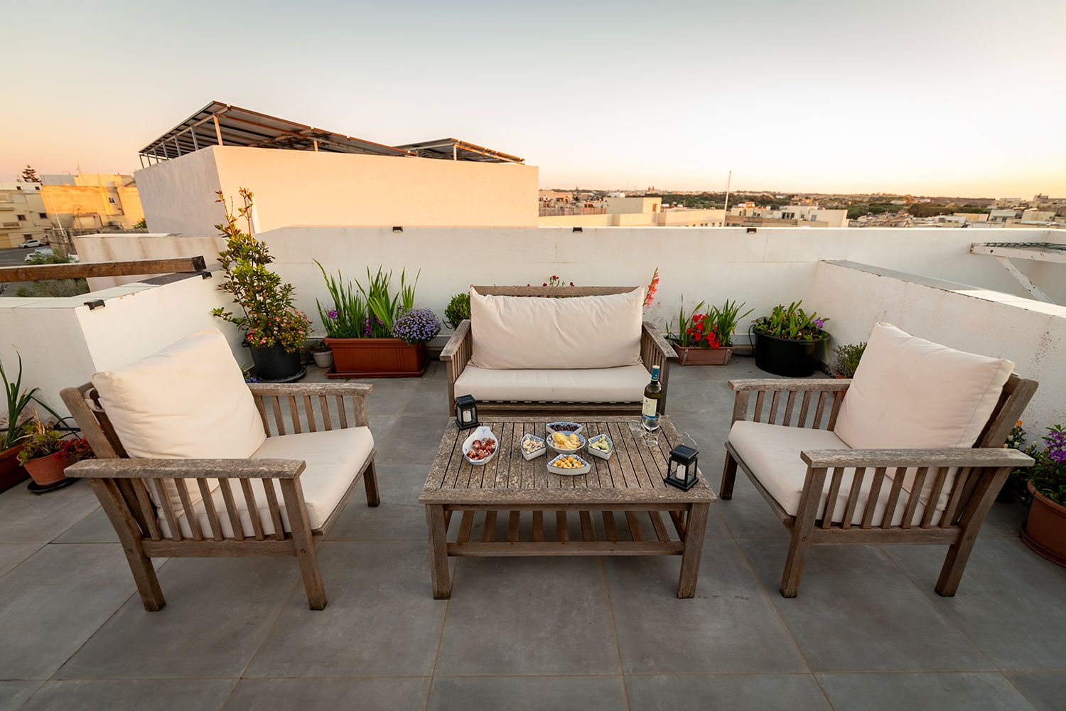 Une terrasse sur le toit, aménagée avec des espaces de détente en plein air, des plantes en pot et une table dressée pour les repas.