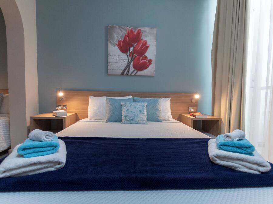 A hotel room with a bed, two nightstands, a painting, and towels.