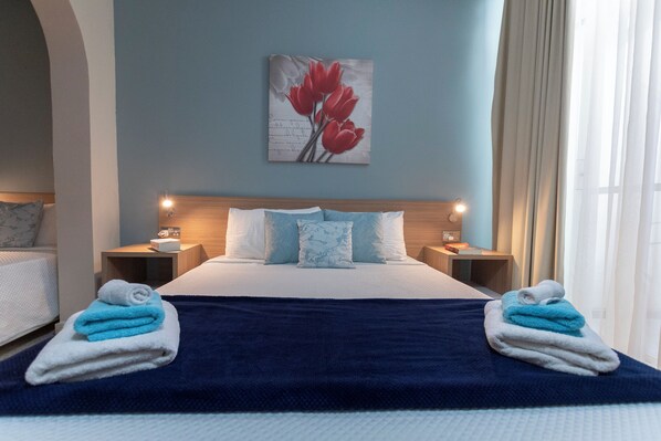 A hotel room with a bed, two nightstands, a painting, and towels. - Estrella Lodging (Rabat)