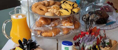A breakfast buffet with various food items, including fruits, pastries, and condiments.
