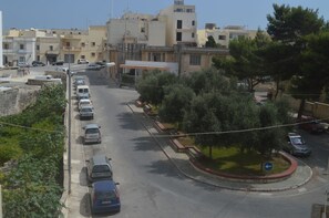 A street view with parked cars, a roundabout, and buildings in the background. - Estrella Lodging (Rabat)