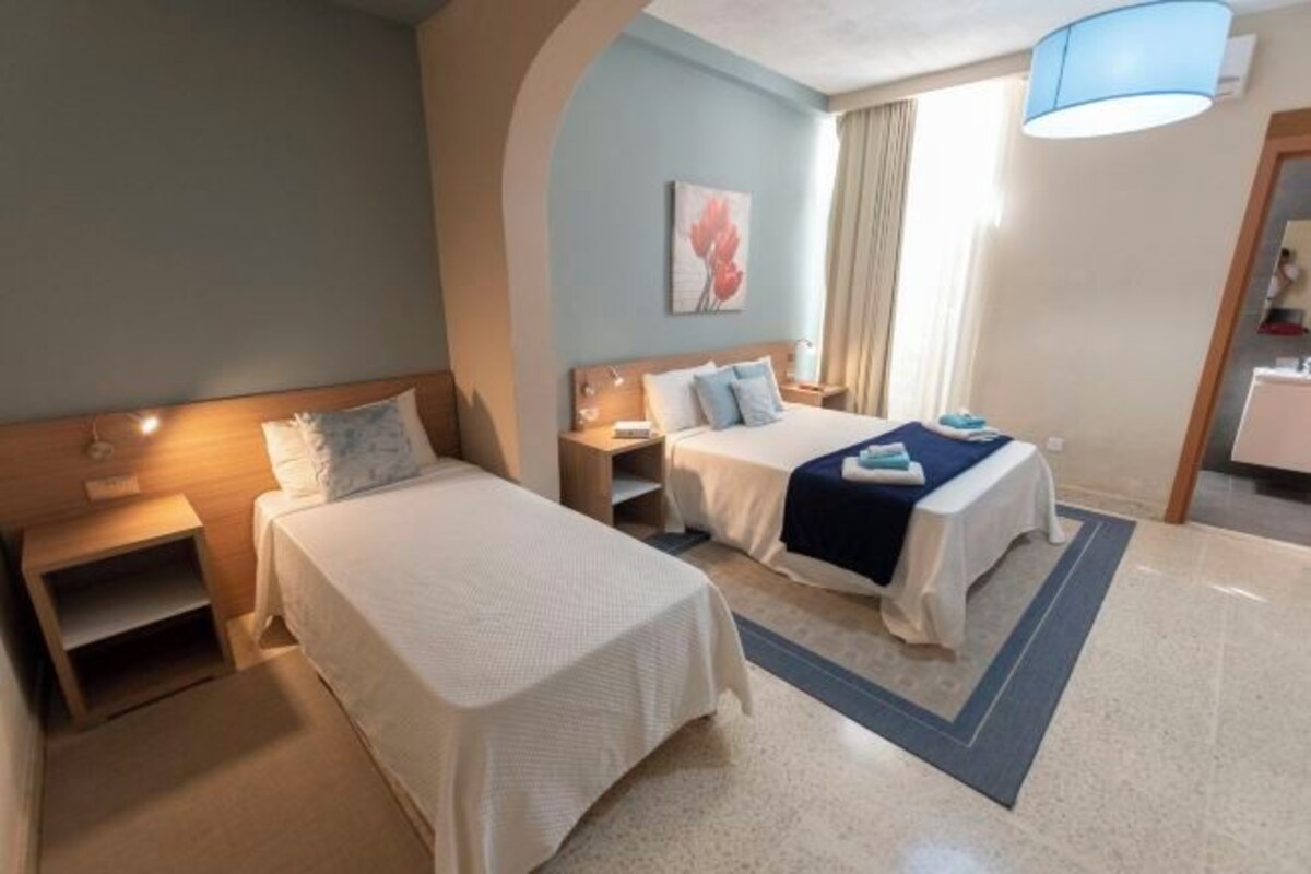 Une chambre d’hôtel avec deux lits, une table de chevet, une lampe et un tableau au mur.