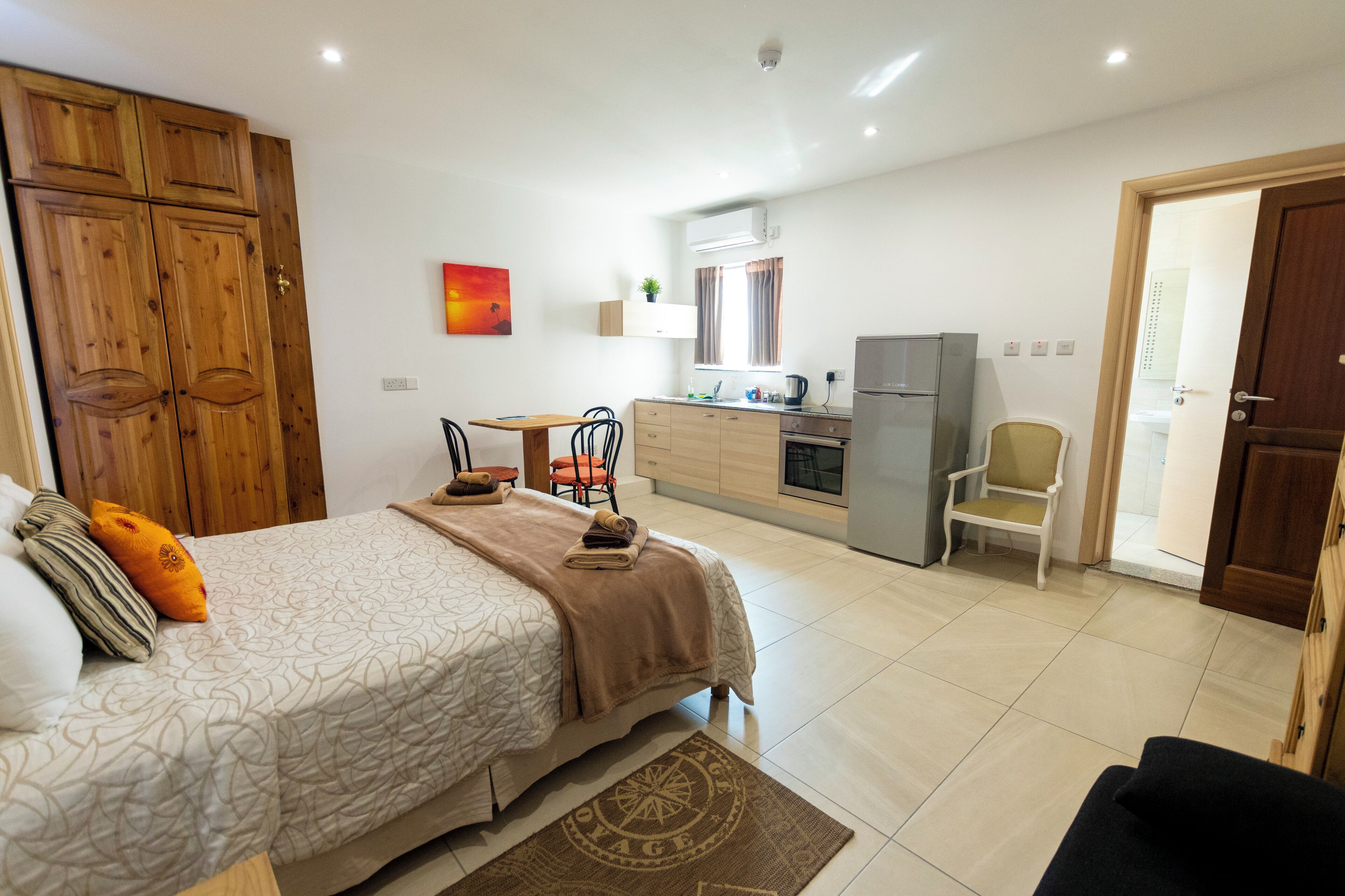 Un dormitorio con cama, escritorio y kitchenette.