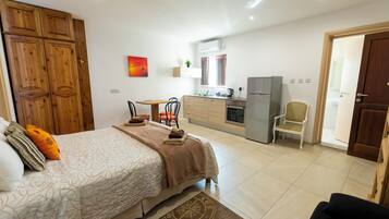 Un dormitorio con cama, escritorio y kitchenette.