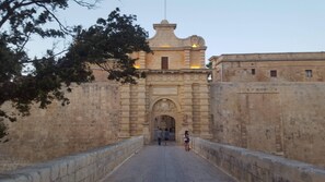 A stone archway leading to a building with a bell tower. - Estrella Lodging (Rabat)