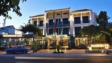 A hotel with a modern facade, multiple balconies, and a well-lit entrance.