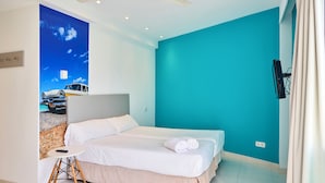 A hotel room with a bed, a small table, a ceiling fan, and a wall with a car image. - Hostel Floridita Adults Only (Calvia)