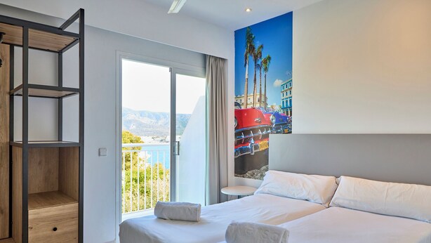 A hotel room with a bed, a wooden shelf unit, and a painting of a red car and palm trees. - Hostel Floridita Adults Only (Calvia)
