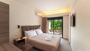 A modern hotel room with a large bed, a nightstand, a TV, and a sliding glass door to an outdoor area. - Hippocampus Hotel (Rhodes)