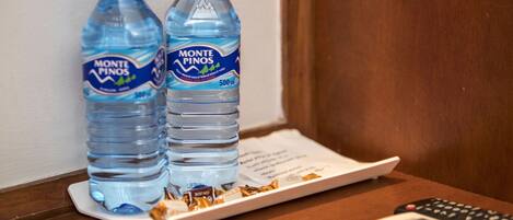 Two bottles of Monte Pinos water on a tray next to a remote control.