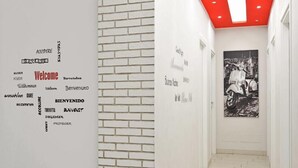 A hallway with a white brick wall and a red ceiling. There is a black and white photograph on the wall. - Black & White G&G (Rome)