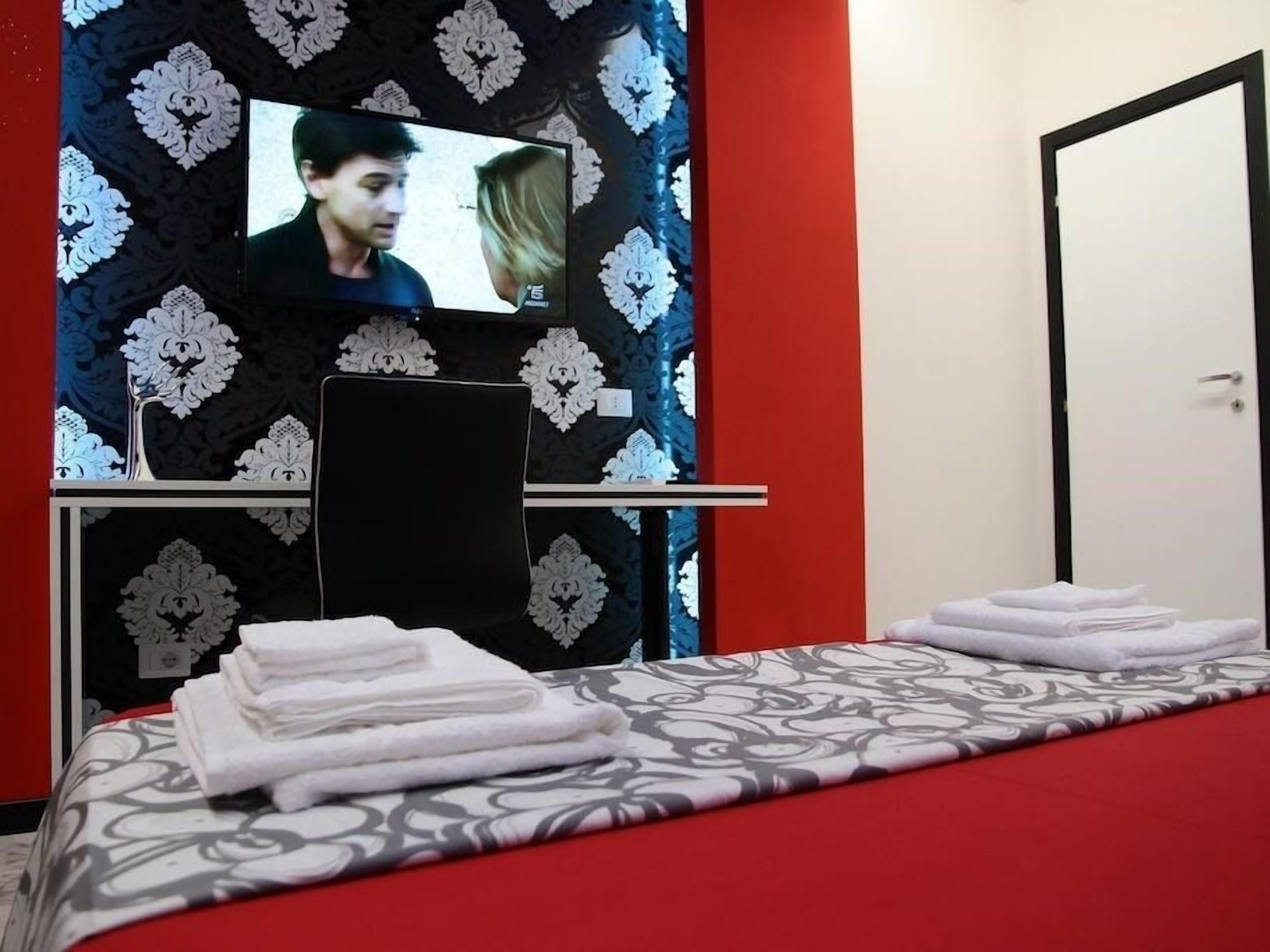 A hotel room with a bed, a TV mounted on the wall, and a door.