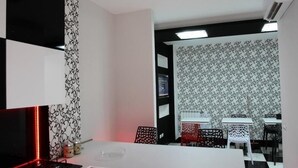 A modern kitchen with a white countertop, black and white patterned wallpaper, and a red-lit stove. - Black & White G&G (Rome)