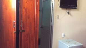 Een kamer met een houten deur, een witte wasmachine en een aan de muur bevestigde televisie.