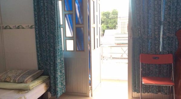Ein Zimmer mit einem Bett, einem Sessel und einem Fenster mit Vorhängen.