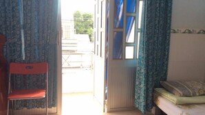 Een kamer met een bed, een stoel en een deur naar buiten.