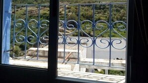 Ein Balkon mit Metallgeländer und Blick auf eine gebirgige Landschaft.