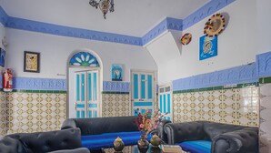 Ein Wohnzimmer mit einer schwarzen Couch, einem Couchtisch mit Dekoration und einer Wand mit blau-weißem Muster.