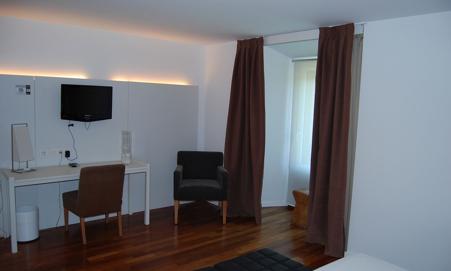 Habitación con escritorio, silla, televisor y ventana con cortinas.