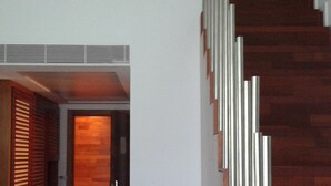 A modern interior with a wooden staircase and a wall-mounted light fixture.