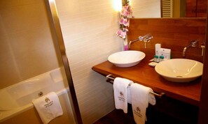 Un baño con bañera, dos lavamanos y un mueble de tocador de madera.