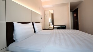 A hotel room with a large bed, a desk, and a mirror. - b_smart motel Basel (Basel)