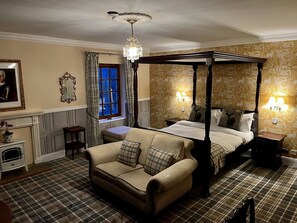 Une chambre à coucher avec un lit à baldaquin, un canapé, une cheminée et un papier peint à motifs.