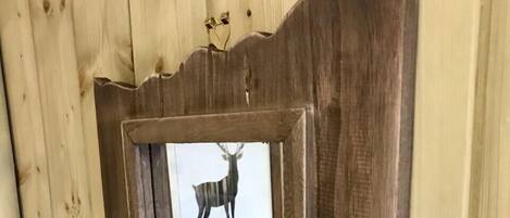 A wooden wall with a framed picture of a deer.