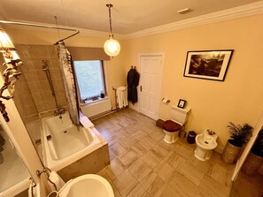 Une salle de bain équipée d’une baignoire, de toilettes, d’un bidet et d’une fenêtre donnant sur l’extérieur.