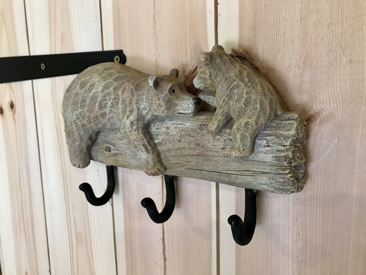 A rustic wooden wall-mounted coat rack with three hooks.