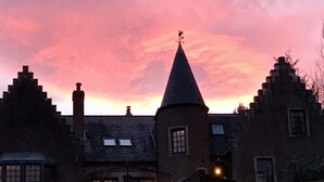 A traditional building with a conical roof, multiple chimneys, and a small tower with a weather vane. - Highland Bear Lodge & Woodland Bear Huts (Inverness)