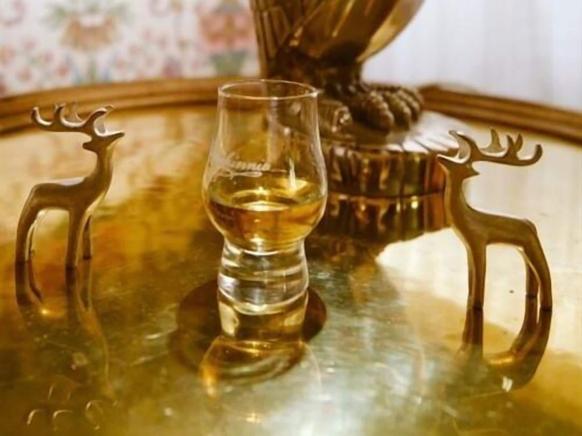 Un verre de whisky sur un plateau doré dont les anses sont en forme de renne.