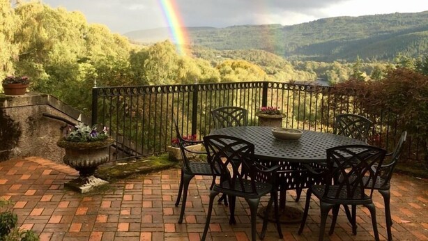 A patio with a round table and chairs, surrounded by a brick wall and a metal railing. - Highland Bear Lodge & Woodland Bear Huts (Inverness)